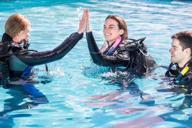 dive instructor high fiving their student in a pool